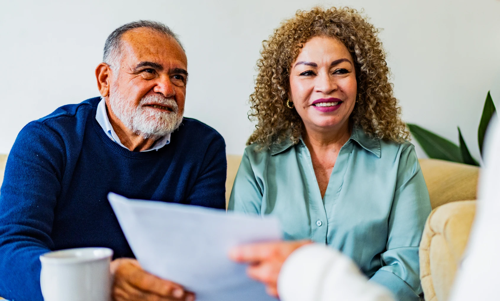 Smiling couple holding documents on the couch